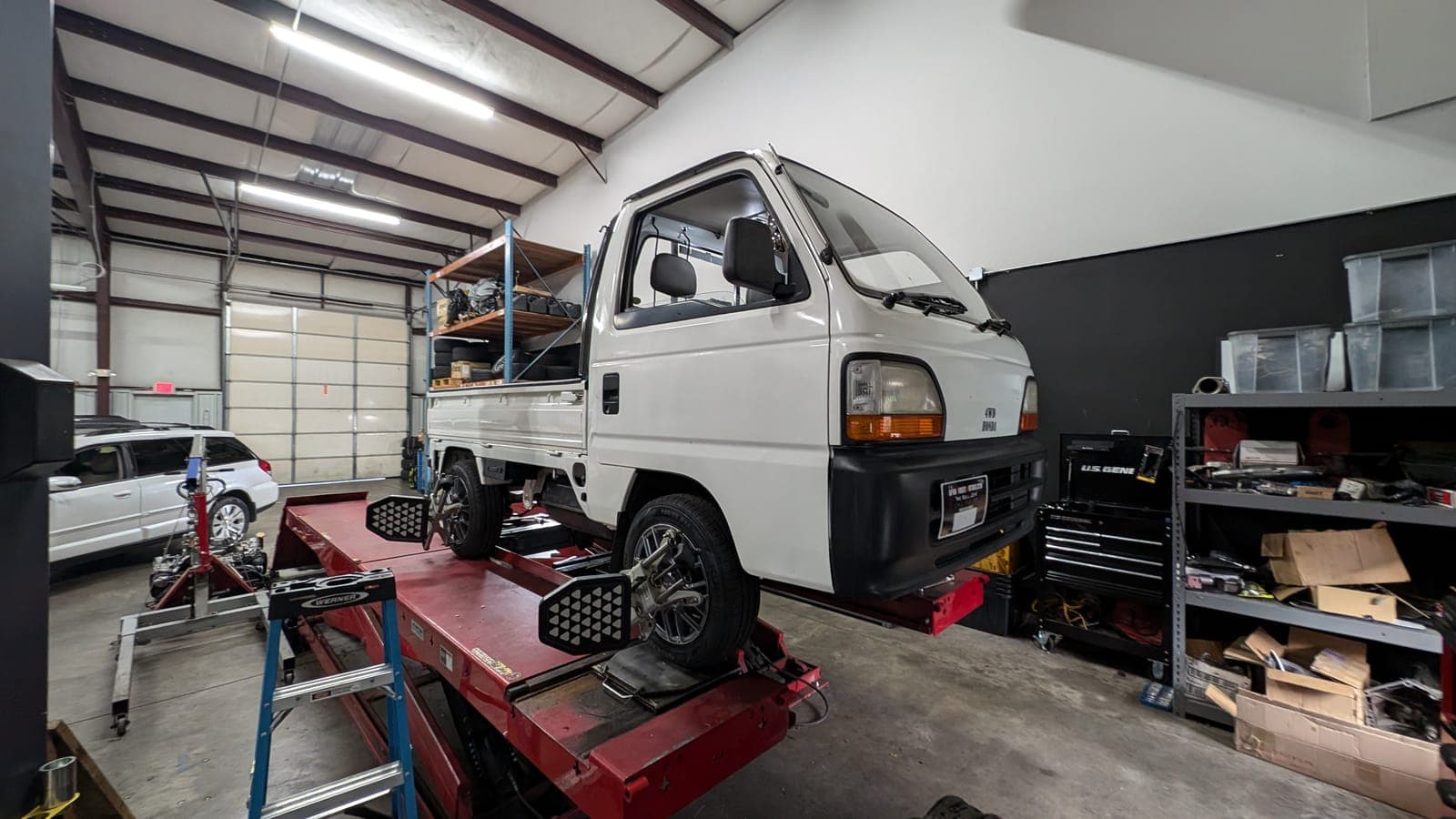 White Honda Acty kei truck on the alignment rack inside the Concord shop