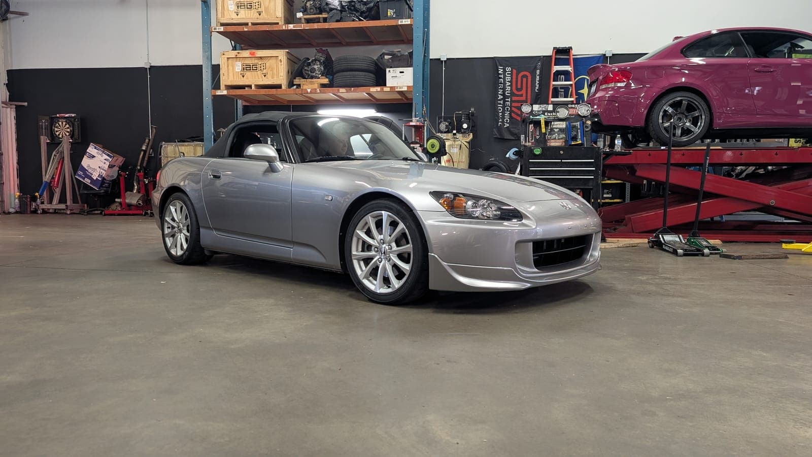 Championship White Honda Civic Type R FL5 on black wheels on the shop floor with a silver Honda S2000 behind it