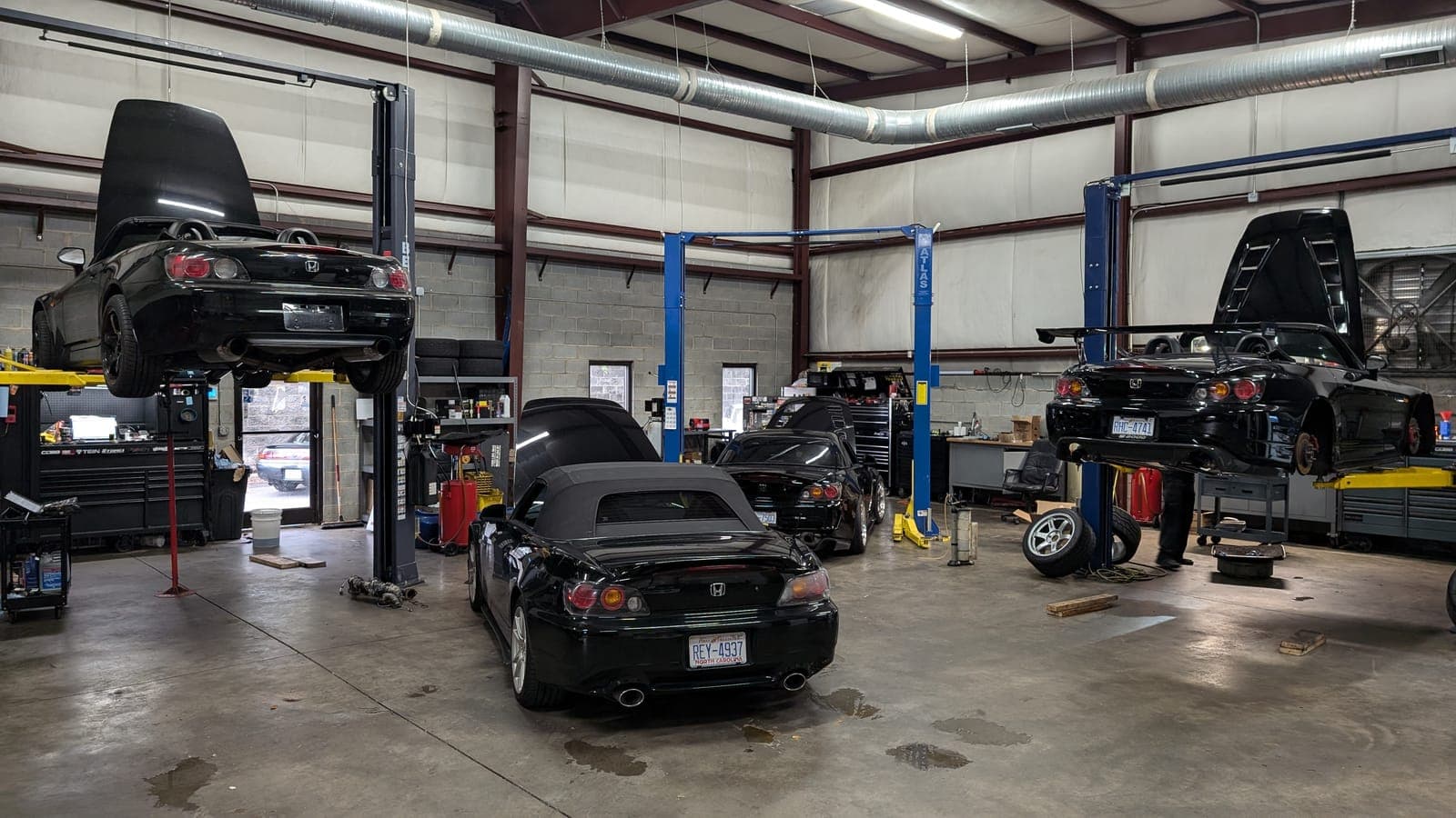 Three black Honda S2000s in the Streamline Performance Garage service bays in Concord, NC, two raised on lifts
